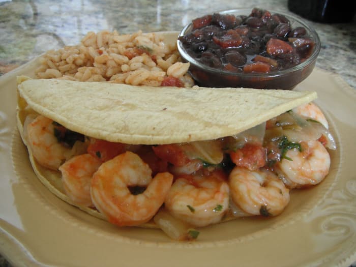 Soft corn tortillas brimming with shrimp, caramelized onions, diced tomatoes, and cilantro; especially delicious with guacamole. Served with rice and black beans on the side.