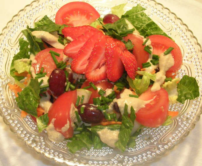 A beautiful salad lightly dressed with Sally's oil-free dressing. Romaine lettuce, carrots, grapes, apples, tomatoes, chives, and an elegant strawberry.