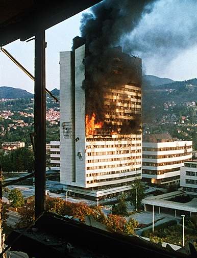 Sarajevo government building burns after being shelled by Serbian tanks (1992)
