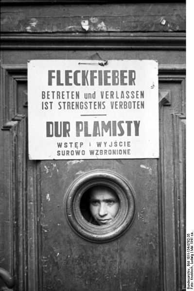 WW2: Poland, Warsaw ghetto. Boy looking through a door, under Typhus quarantine. Entering and leaving is strictly prohibited.