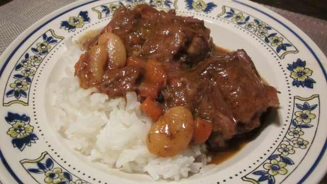A bowl of steaming hot Jamaican-style oxtail stew served over fluffy white rice is a flavorful taste of the Caribbean.