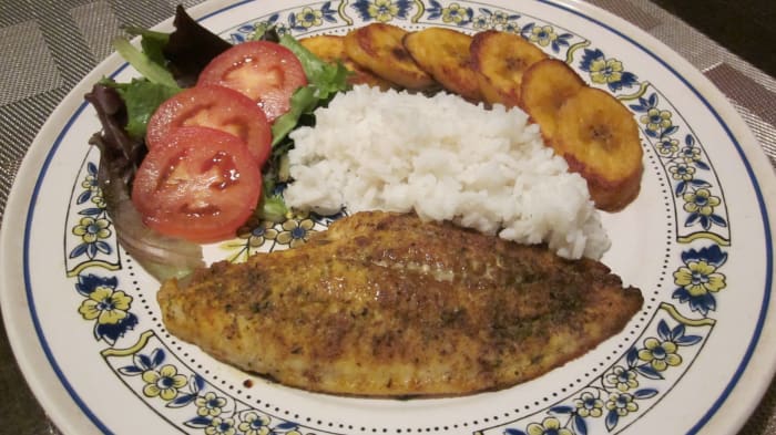 Curry catfish with white rice, fried plantain, fresh spring mix salad and plum tomato slices.