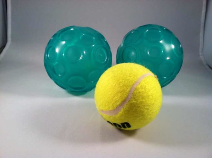 Types of balls for self-massage (textured Franklin balls in back, tennis ball in front).