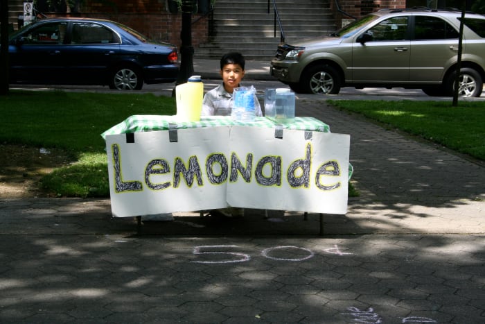 A young entrepreneur selling lemonade at a very affordable price; finding the right price is the key to success.