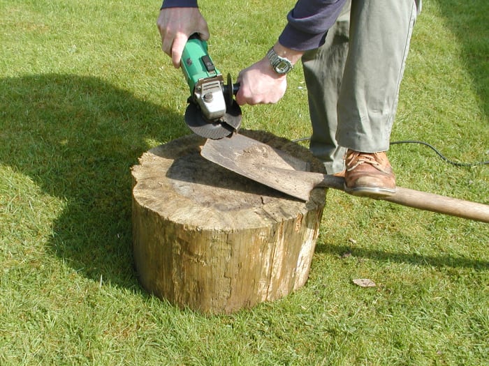 Place your foot on the spade to steady it. Angle the grinder at about 30 degrees to the plane of the blade