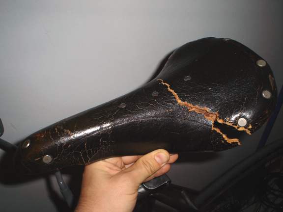 This dry rotten leather seat is falling apart, the leather is breaking apart because the fibers are so dry and crumbly.