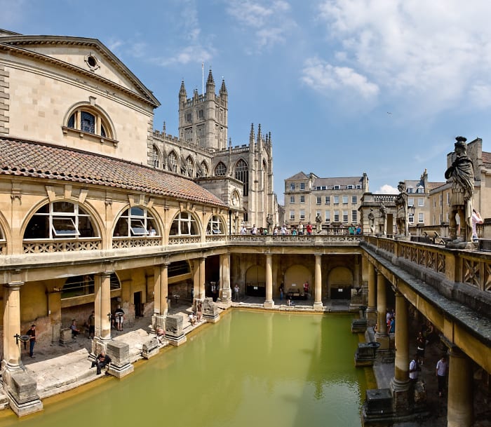 The Great Bath in the city of Bath, England; the bath, the light grey base of the surrounding pillars, and the passageway date from Ancient Roman times