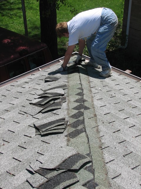 removing the extra layer of asphalt shingles on one of the ridges to make a flush surface for the foam board