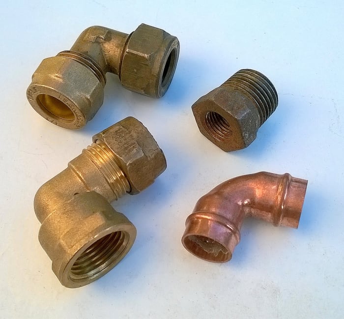 Clockwise from top left: compression elbow, iron reduction bushing with BSP threads, copper capillary elbow, and compression elbow with 1/2 inch threaded BSP port.