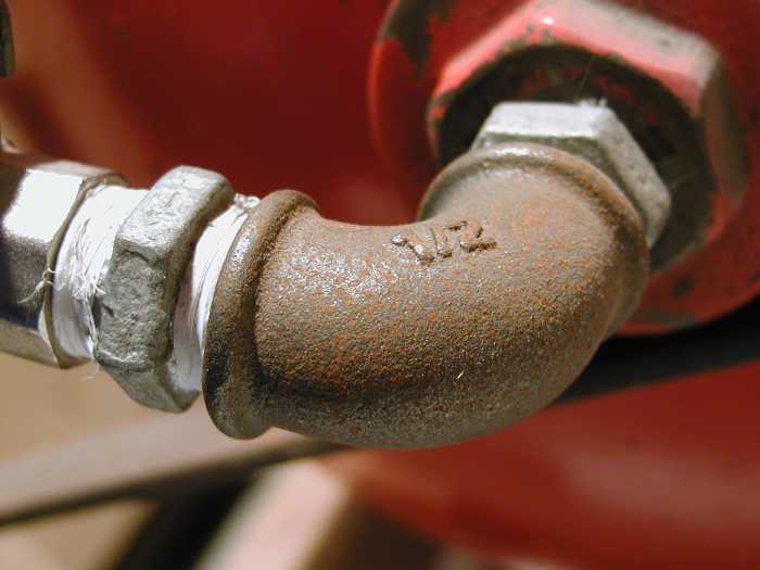 This 1/2 inch, malleable-iron, 90° elbow, used on the output of an air compressor, has female BSP threads.