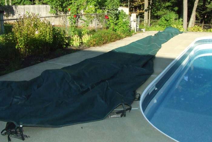 Lay out the cover on the side of the pool so you can slide it over the pool easily. It's nice to have two people when installing the cover, but not necessary.