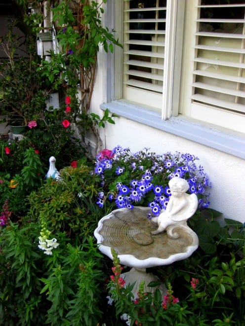 This East facing bed is full of partial sun plants and features a trellis of birdhouses and a cherub birthbath. | Source