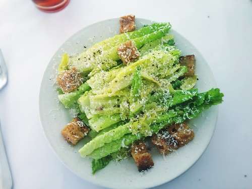 Caesar salad typically includes romaine lettuce, Parmesan cheese, croutons, dressing, and black pepper.