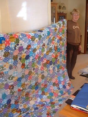 Margaret (student) shows the hexagon quilt she completed from the many hexagons made by her mother from family scrap fabrics.