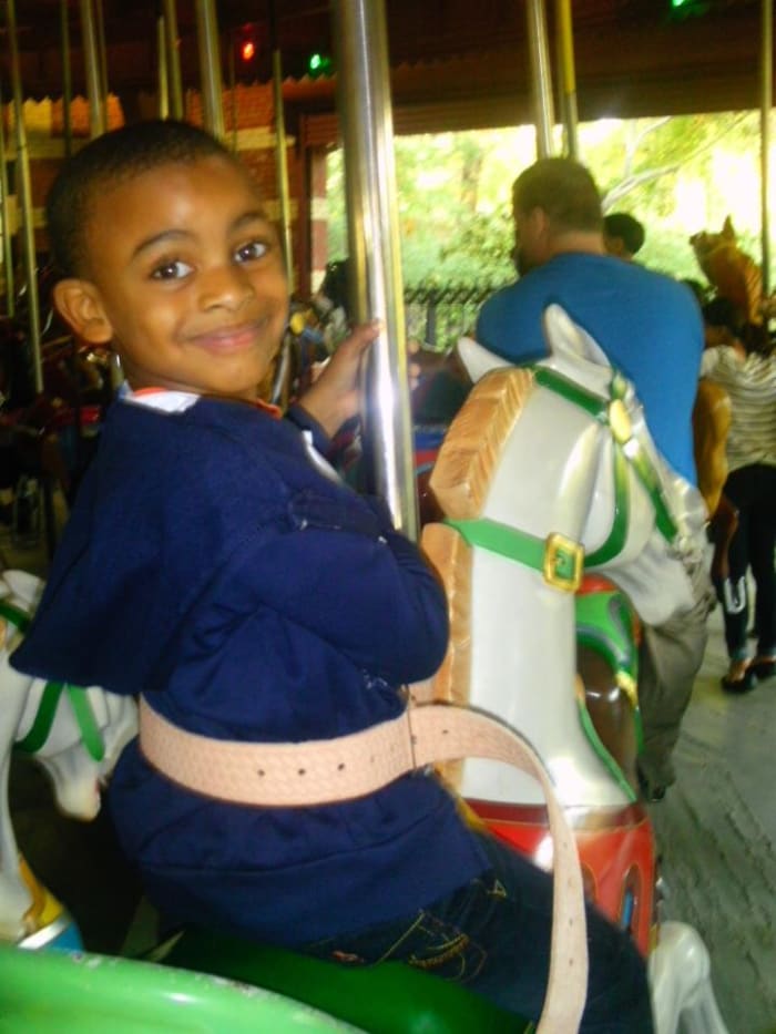 L'image de l'enfance - chevauchant joyeusement le carrousel de Central Park tout en regardant une caméra.