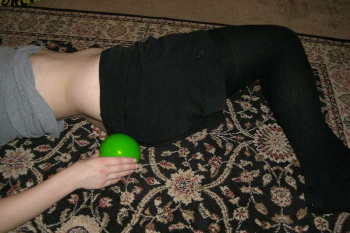 Tuck the ball under by rolling to your side, and then gently rolling back onto the ball. Don't put the ball anywhere that is uncomfortable. If it is uncomfortable, find a better spot.