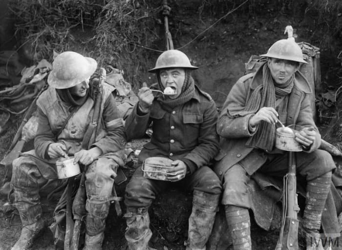 Mud-caked British soldiers enjoy a meal away from the front line during the Battle of the Somme in October 1916.