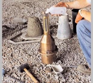 Here, a man is pouring alcohol into the neck of a rollermeter as part of the procedure to find the volumetric air content of concrete.