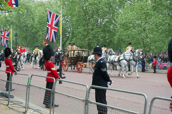 The Queen of England arrives by carriage at a royal wedding