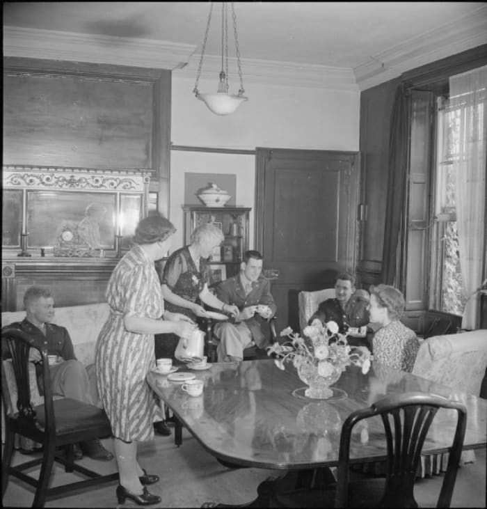 Photograph of American soldiers having afternoon tea in Winchester, England. (ca. 1944). Photographer unknown, of the Ministry of Information Photo Division. Work is in the public domain.