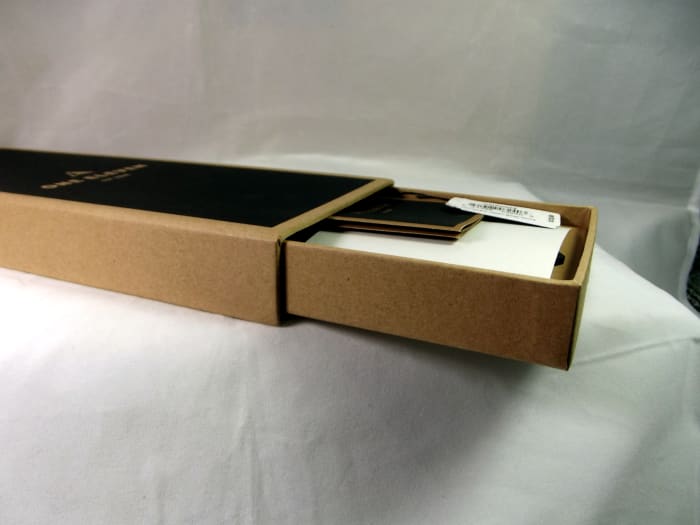 Box containing a One Eleven CMP0002 solar powered quartz watch with leather strap. This box is composed of recycled cardboard