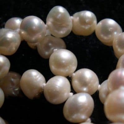 Telltale signs include surface imperfections, shape irregularities, color gradients in the nacre, luster, and the knots between each gem.