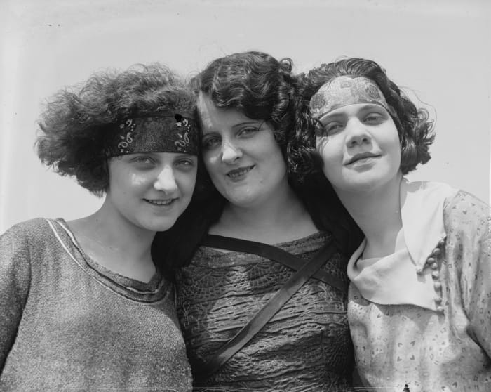 The crimped, bobbed hair; horizontal headbands; and jaunty air date this photo to the 1920s.