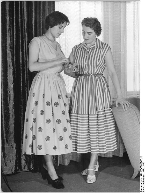 Short hair; longer and wider skirts date this pic to the 1950s.
