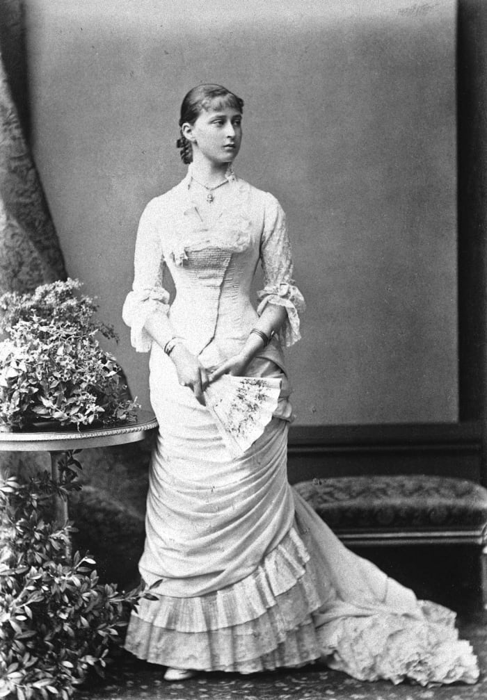 Note the horizontal, slightly diagonal draping of the narrow skirt. Bodice flares below the waist and fits the hips. Also note bangs indicating. Circa early 1880s