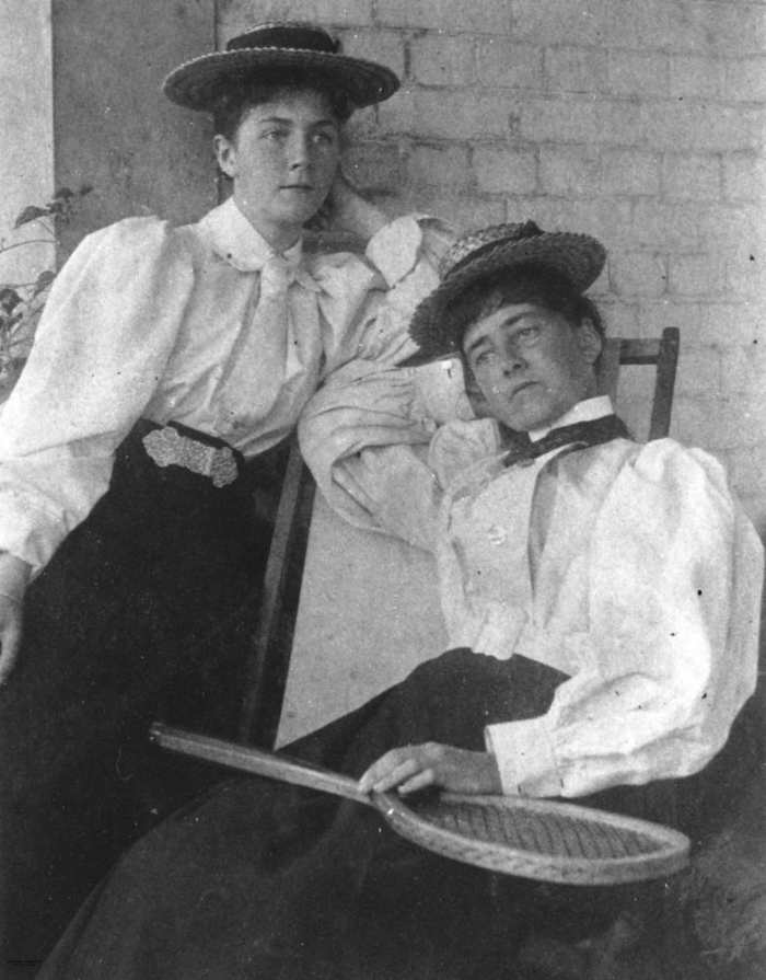 Note large sleeves; light blouse tucked in dark skirt, ties, and straw boater hats suggest the 1890s.