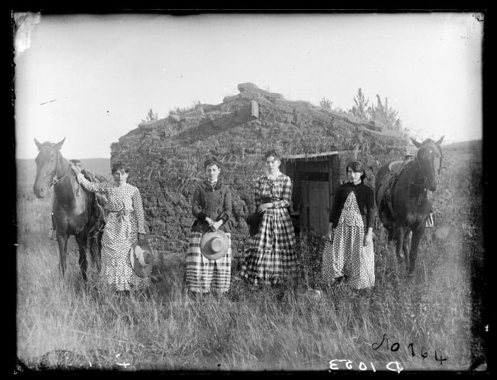 The Chrisman sisters pose in front of a sod house.