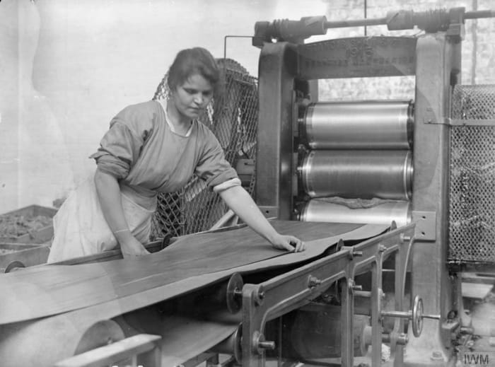 A worker operates a calendaring machine in the rubber factory of Charles Macintosh and Sons Ltd, Manchester, England, September 1918.