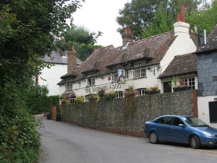 The Shepherd & Dog in Fulking, Sussex; a path to the right starts its ascent to the top of the Sussex Downs