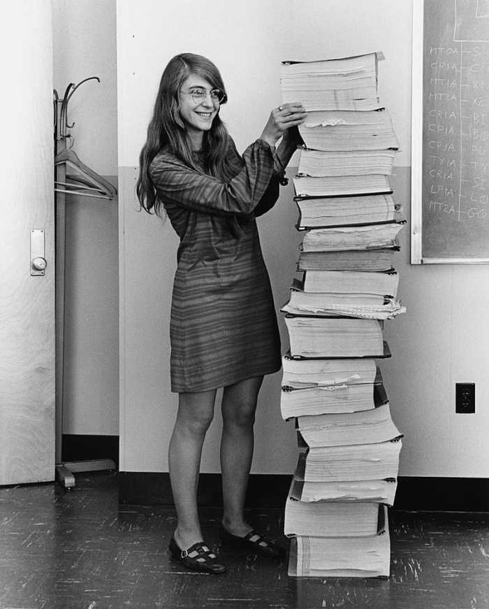 Hamilton in 1969, standing next to a stack of navigation software that she and her MIT team produced for the Apollo project.