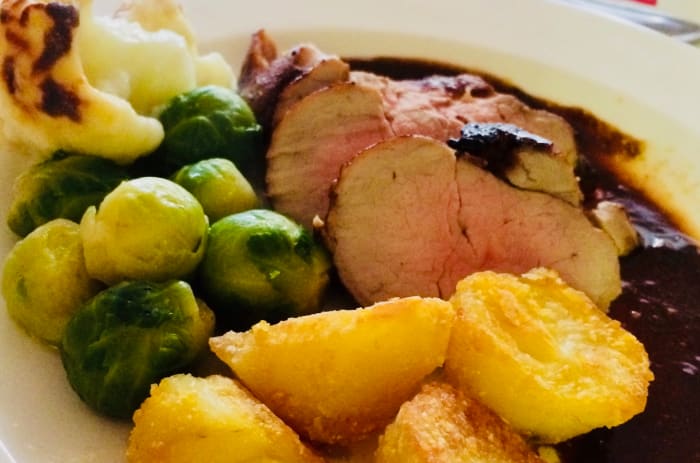 Roast pork loin: semolina roast potatoes, buttered sprouts and cauliflower cheese with orange and balsamic glaze.