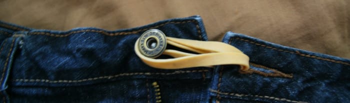 Use a rubber band and loop it through the button-hole. This gives a little more room in the waist-band for those who aren't quite ready for maternity pants, but have bloating in early pregnancy!
