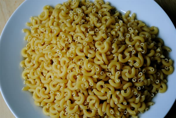 Because dried pasta hasn't absorbed the water yet, simply pour it into the bowl you will serve it in and fill it just below the point at which you want your cooked pasta serving to reach. It's inexact, but it works pretty well.