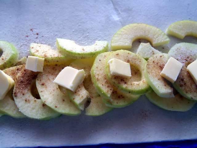 Lay out a row of apples and sprinkle with cinnamon and sugar. Add the cubes of butter.