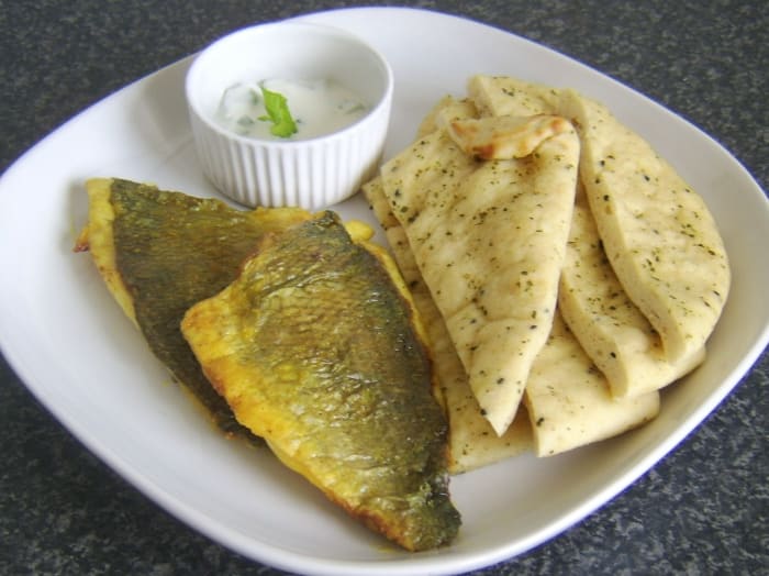 Curry marinated sea bream fillets are shallow fried and served with naan bread and cucumber and mint raita