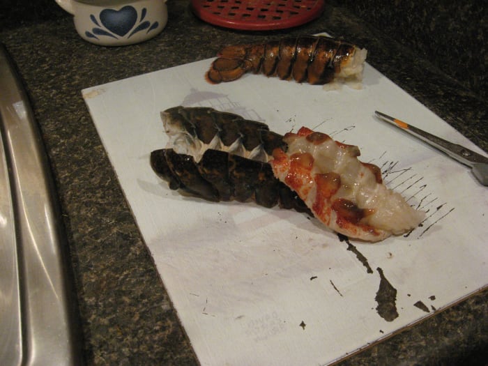 Spread the tail open with your fingers, but don't break any parts of the shell. Flip the meat out, leaving it attached at the base. Add oil and seasonings to both sides of the meat and place back in shell.