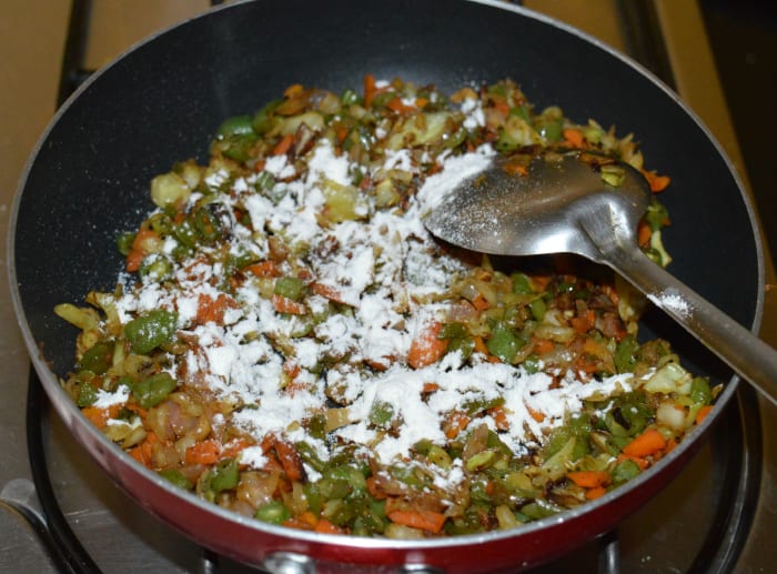 Step five: Sprinkle a few drops of water on the veggies. Add some all-purpose flour. Stir the mixture well. The flour makes a good binding agent. Turn off the heat. The stuffing for the wontons is ready!