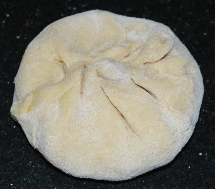 Step four: Divide the dough in many equal portions of a lemon size. Likewise, divide the stuffing in equal number of portions. Take one such dough portion. Shape it like a patty. Roll it into a disc of 3 inch diameter.