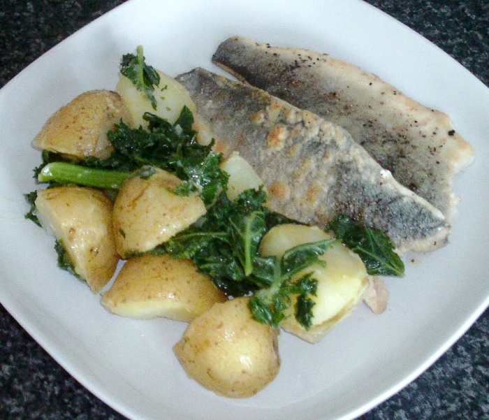 Pan fried sea bass fillets are served with boiled potatoes and kale in a rich and tasty turmeric and tarragon butter sauce