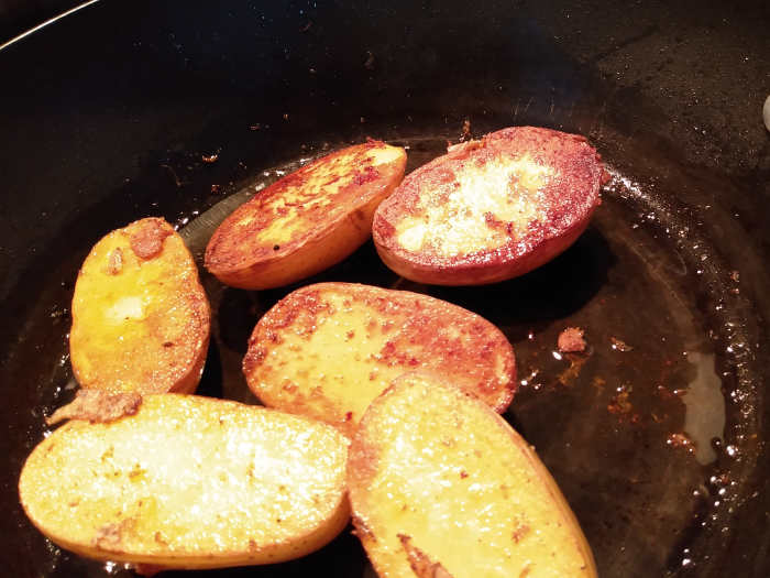 Yukon gold potatoes sliced in half vertically. One side has been sauteed. Look at that rich golden brown color.