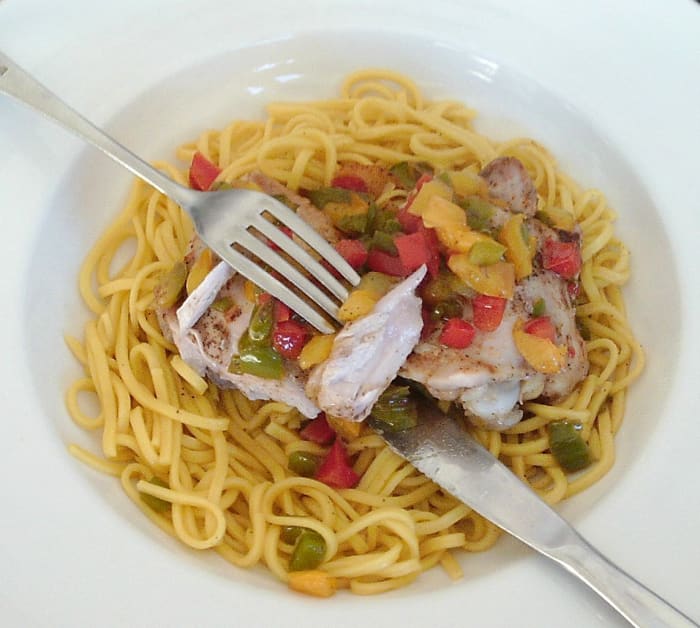 Chicken thighs baked with spices and bell peppers are served on a bed of turmeric spiced egg noodles