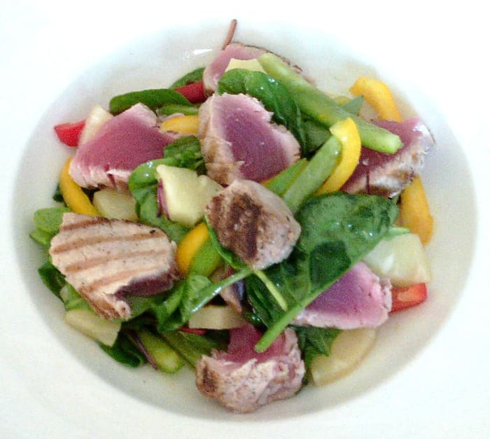 Seared tuna loin slices are served infused in to a pineapple, bell pepper and mixed green leaf salad