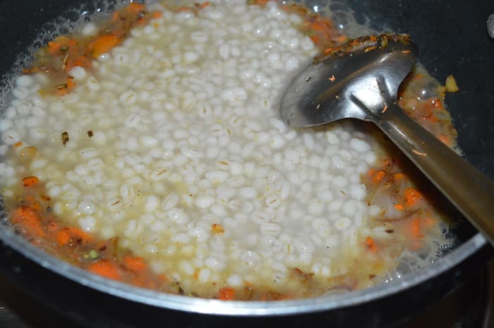 Step two: Add cooked barley along with its water. Also, add coconut milk, milk, and remaining salt. Keep the heat medium-high.