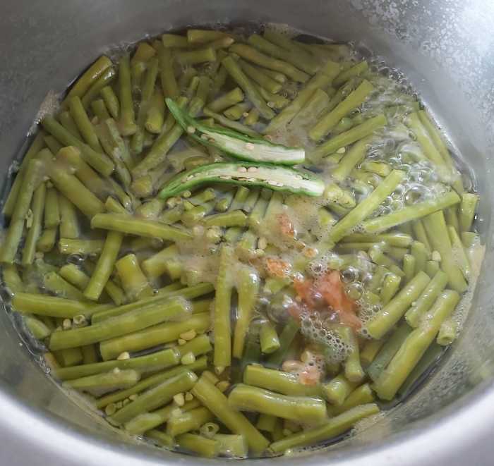 When the long beans are cooked, add 1-2 slit green chilies and 1-2 teaspoons of jaggery. Bring this to a boil.