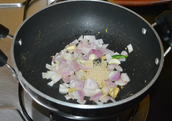 Step three: In the same pan, add some more oil. Add the slit green chilies, chopped ginger, garlic, poppy seeds, and onions. Saute until the poppy seeds become roasted.