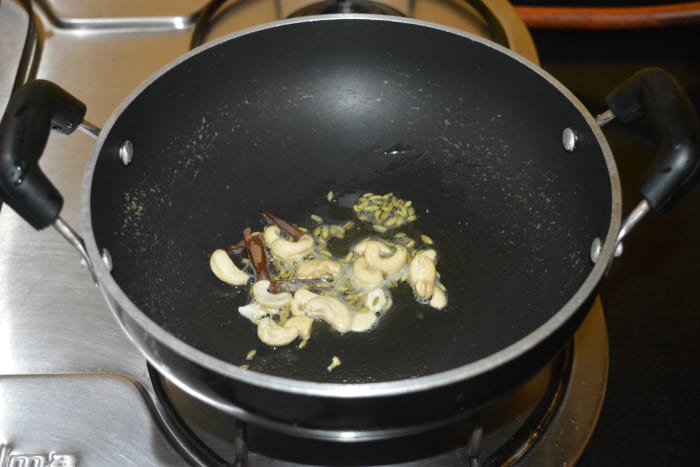 Step two: In the same pan, add some oil. Add cashews, fennel seeds, and cinnamon sticks. Saute until the cashews change color. Remove the mixture and add it to a mixer jar. Set aside.